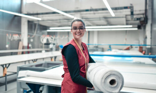 Smiling Female Textile Worker Carrying Heavy Rolled Materials For Printing Roller Machine